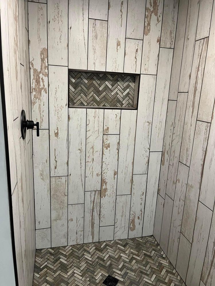 Small rustic wooden door with a black handle and chevron-patterned tile inset.