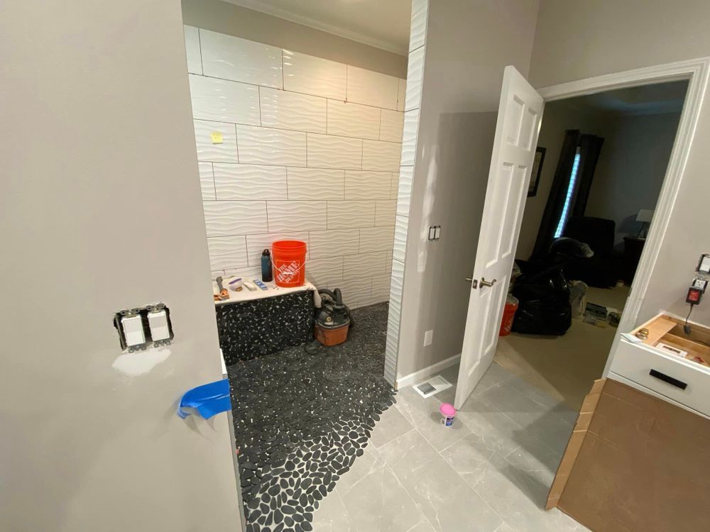 Partially renovated bathroom with tiled walls, black-speckled floor, and cleaning supplies on the vanity.