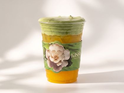 Green and yellow decorated paper cup with a flower embellishment on a white background