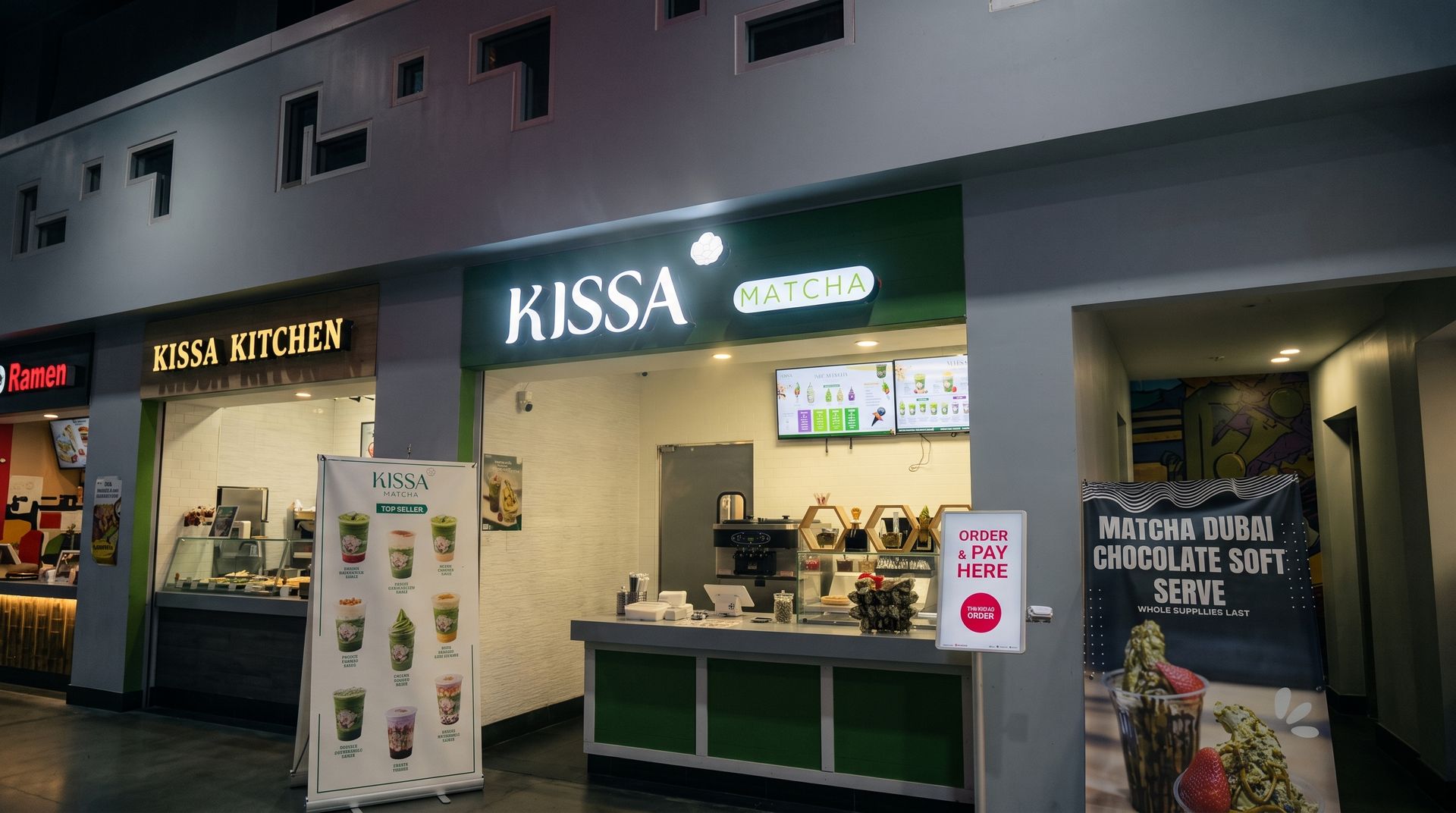 Indoor market stalls with lit food counters, including a green Kissa kiosk and nearby bakery displays