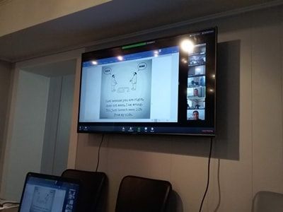 A screen displaying a Zoom call with several participants and a presentation about two pens facing each other.