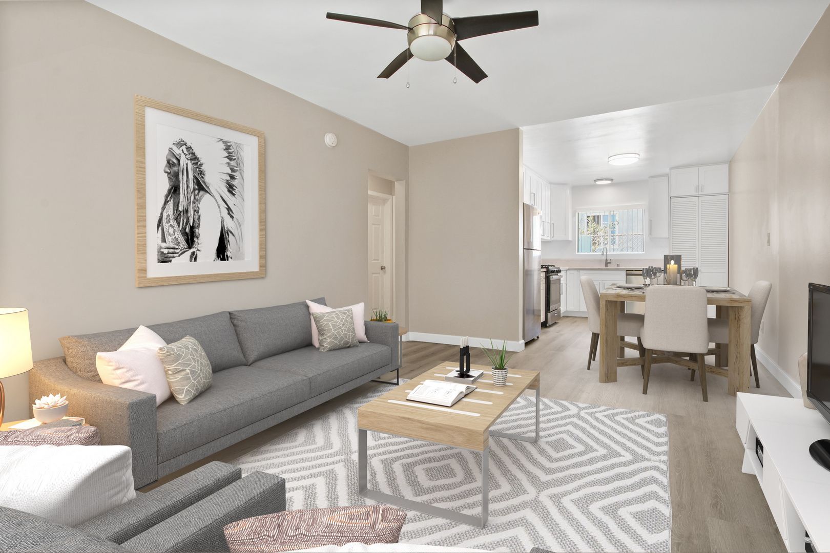 Bright living room with gray sofa, coffee table, patterned rug, and adjoining dining area in neutral tones