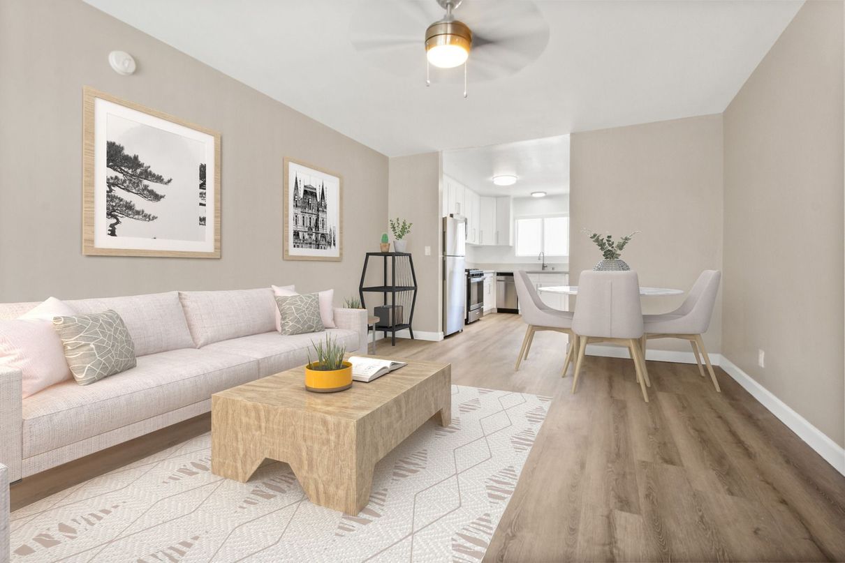 Bright minimalist living room with beige sofa, wood coffee table, dining nook, and light hardwood floors