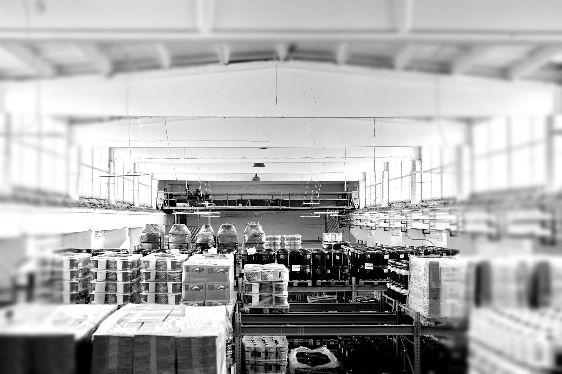 Bright warehouse aisle with stacked pallets and shelves under overhead lights