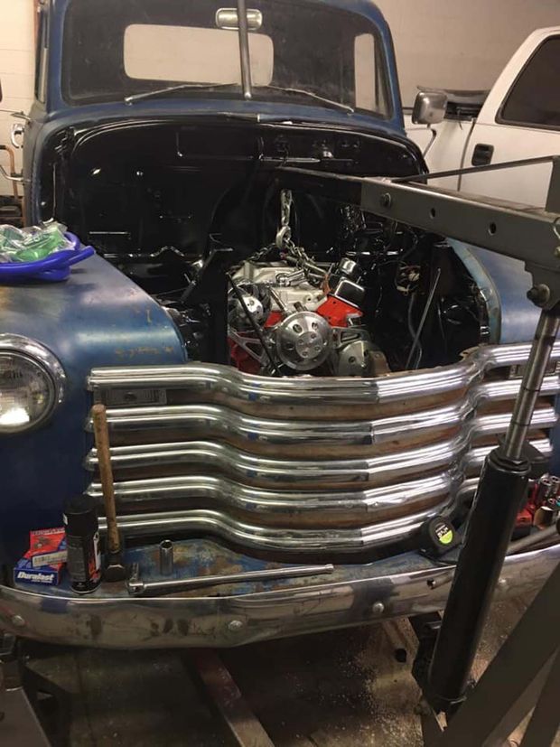 Blue vintage truck with hood open, showing engine in a garage next to another vehicle.