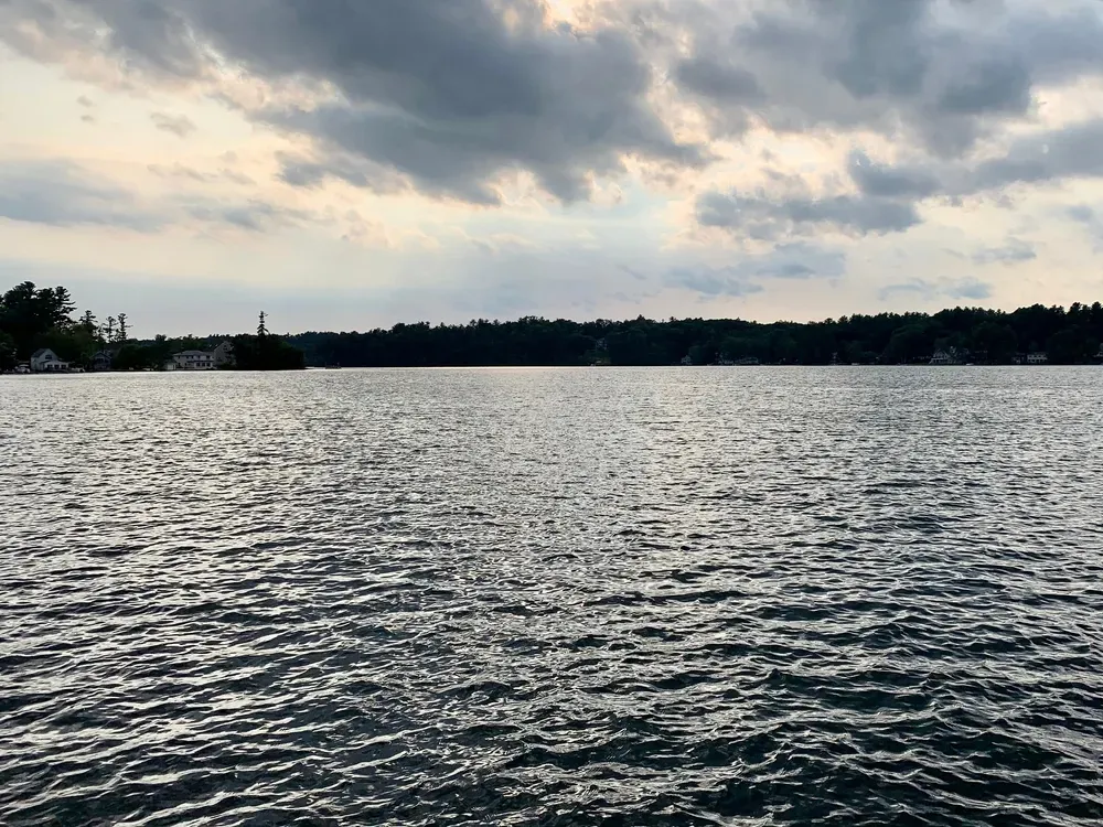 Cloudy sky over a rippled lake with a distant tree-lined shore
