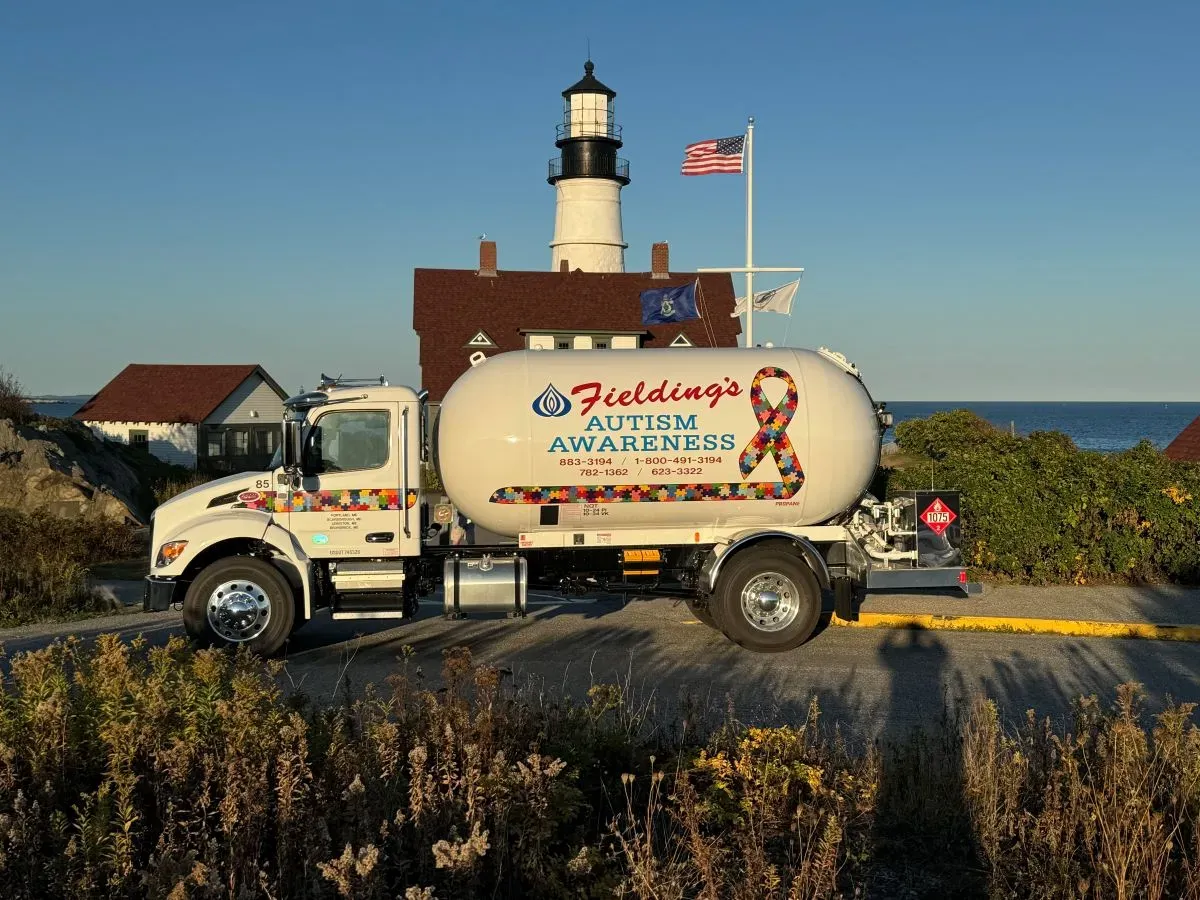 White seafood delivery truck parked by a lighthouse on a sunny coastal road
