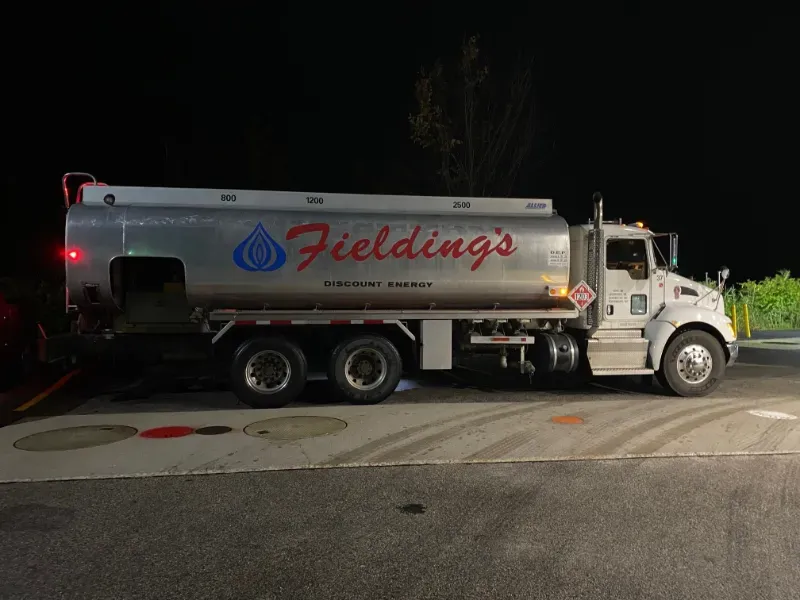 Silver Fielding water tanker truck parked on a street at night.