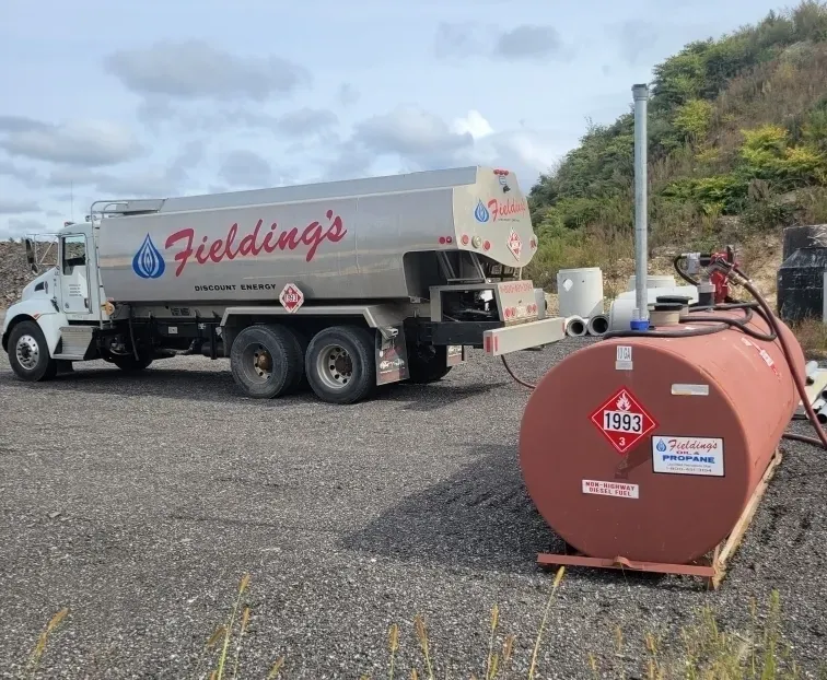 Fielding’s fuel tanker truck beside a red fuel tank on gravel near a hillside