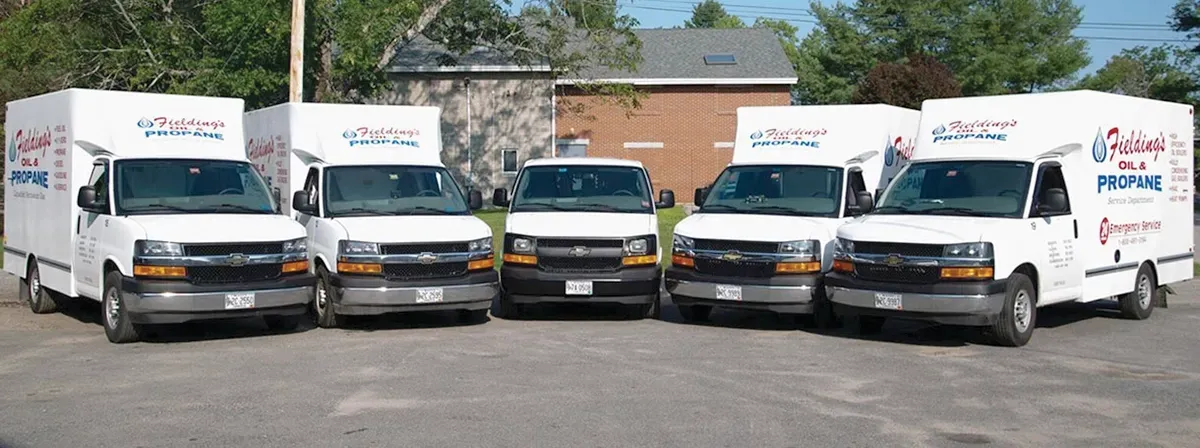 Five white delivery vans parked in a row in front of a building