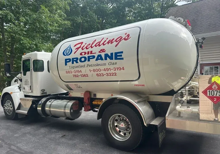 White Fielding’s propane tanker truck parked on a residential street, with trees in the background
