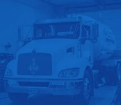 Blue-tinted white tanker truck parked in a snowy lot, front view