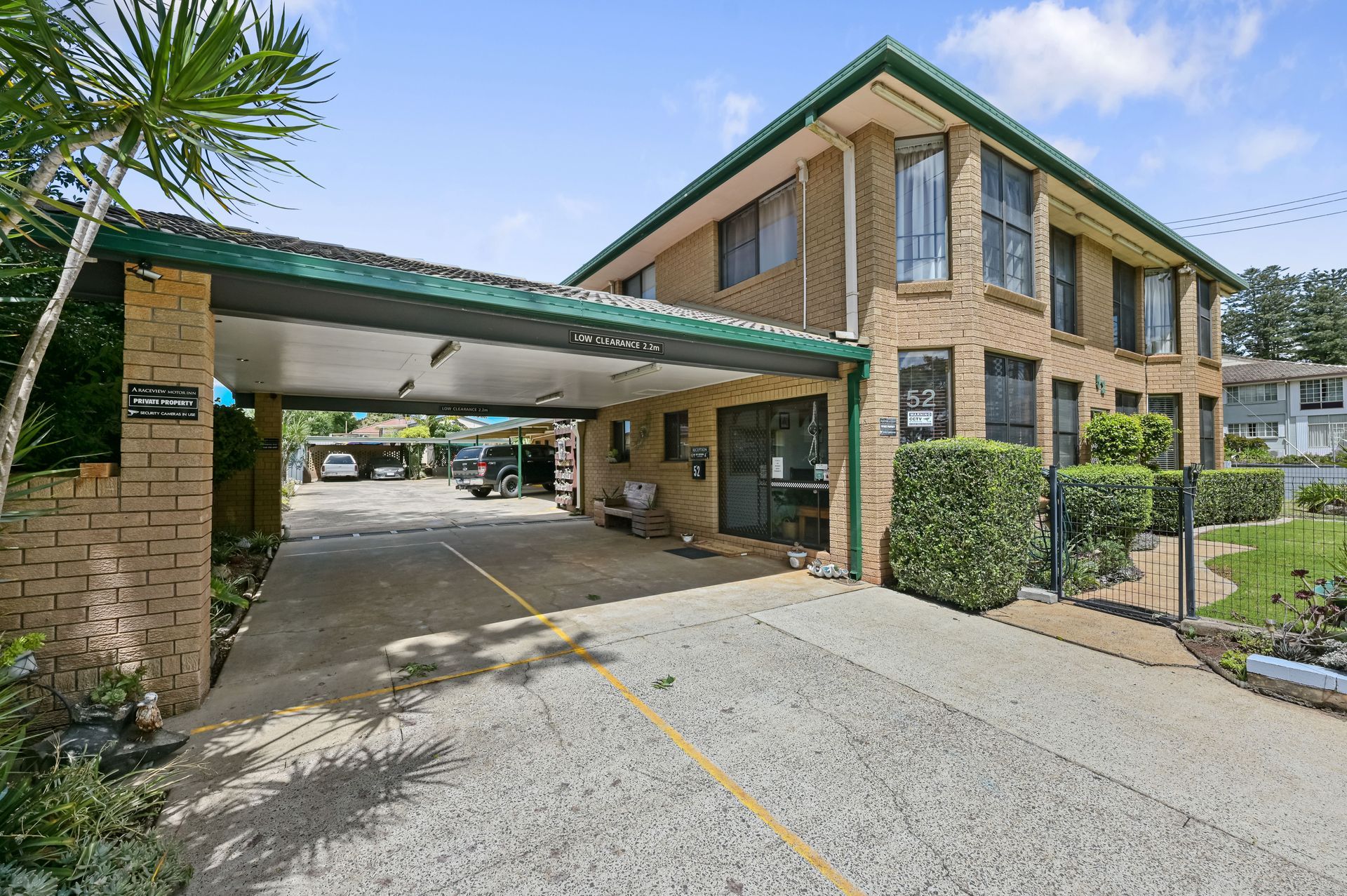 Brick apartment building with green awning and covered driveway, seen from the parking lot