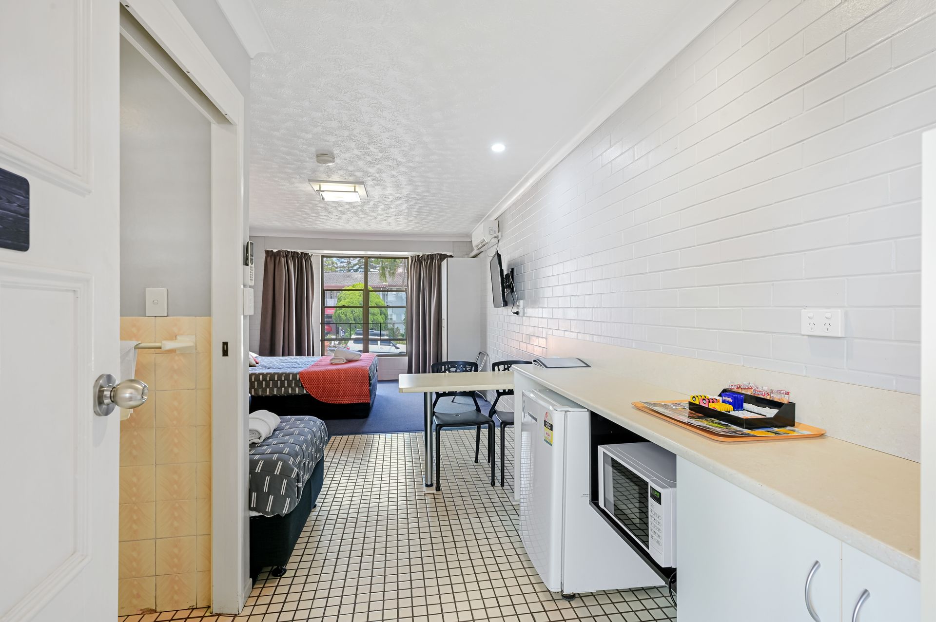 Narrow modern living room with white brick wall, sofa, coffee table, and large window at the end