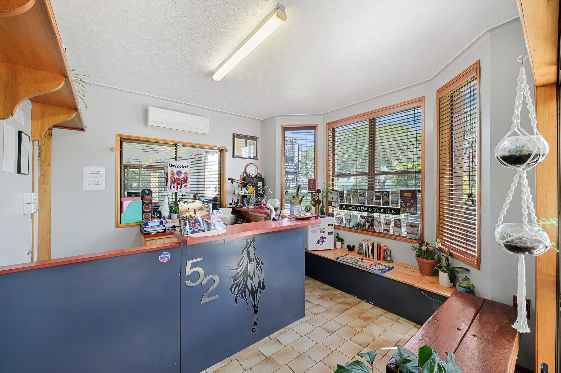 Small shop interior with blue counter, tiled floor, shelves by a window, and hanging silver ornaments