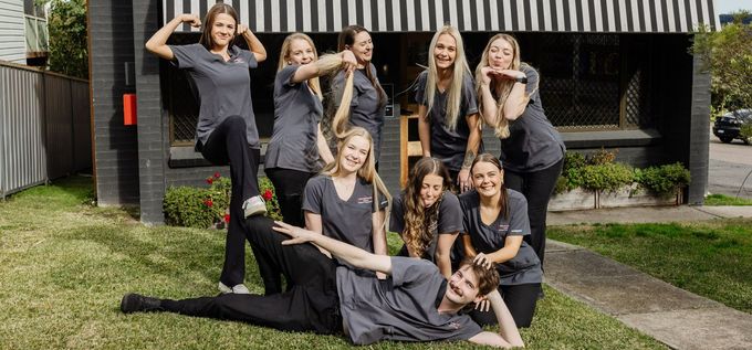 Group of people in matching shirts posing on grass — Westlakes Veterinary Hospital in Fennell Bay, NSW