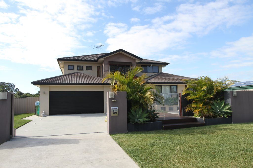 Property valuers Sunshine Coast team assessing a large house with a black garage door — Peterson Property Valuations, Caloundra West, QLD