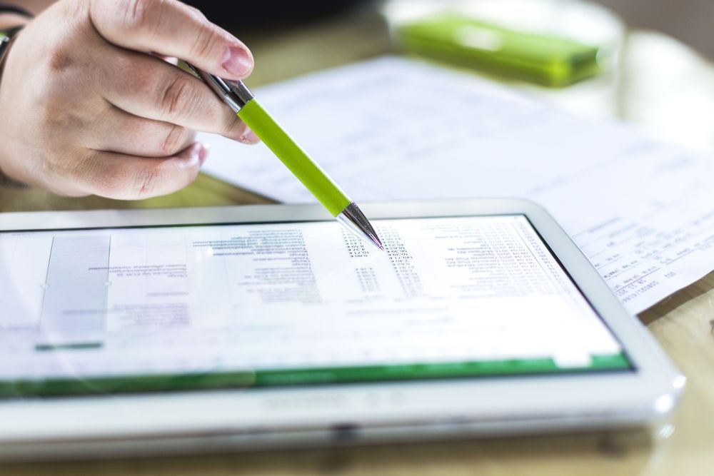 A Person's Hand With a Green Pen Pointing at a Digital Tablet — Peterson Property Valuations In Caloundra West, QLD