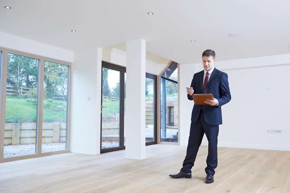 A Man in a Suit and Tie is Standing in an Empty Room — Peterson Property Valuations In Caloundra West, QLD