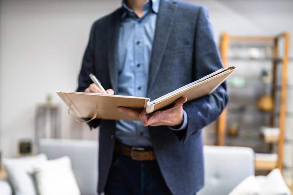 A Man in a Suit is Holding a Clipboard and Writing on It β Peterson Property Valuations In Caloundra West, QLD