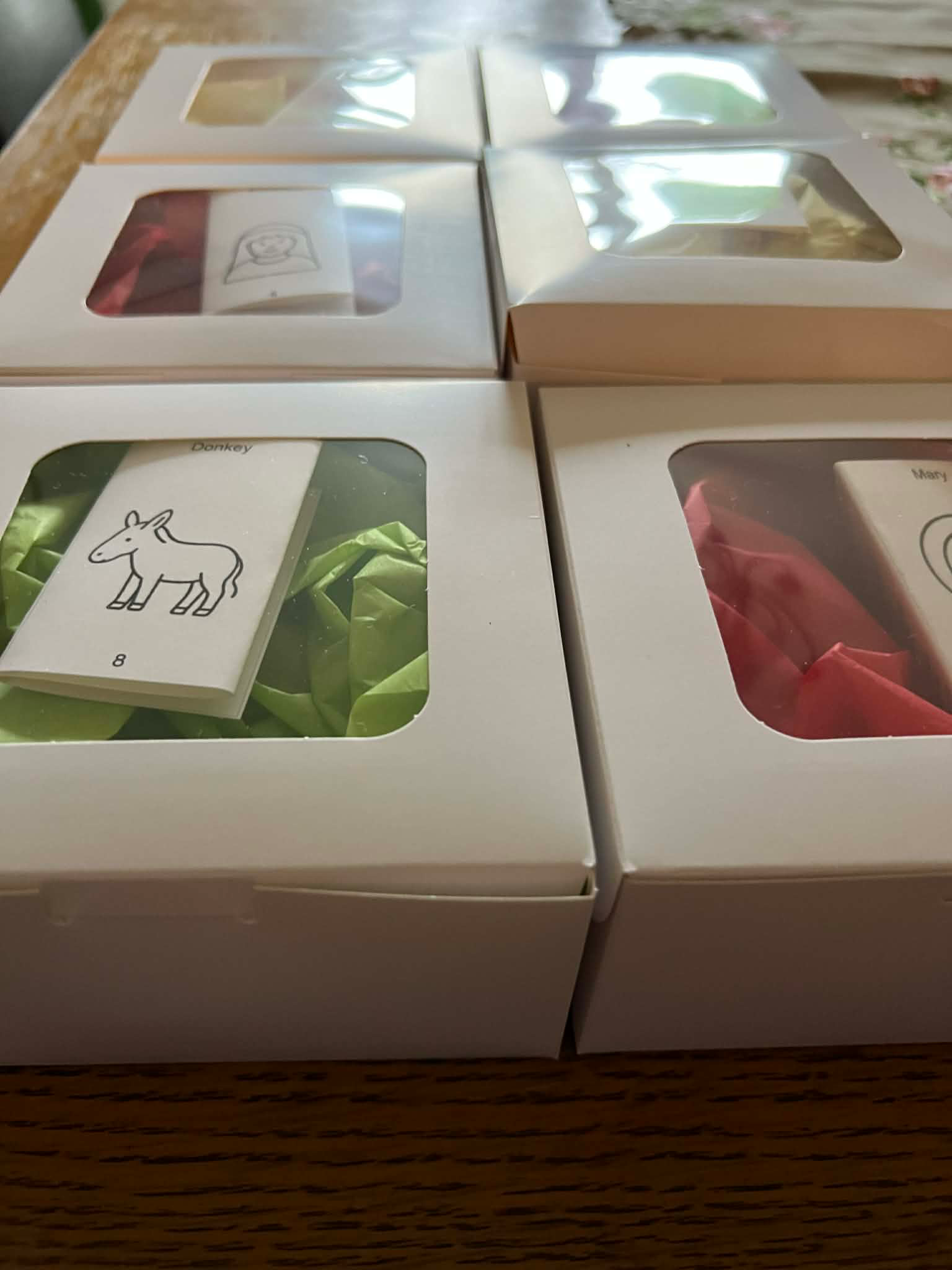 Boxes of assorted gift sets with ribbon and name cards on a wooden table
