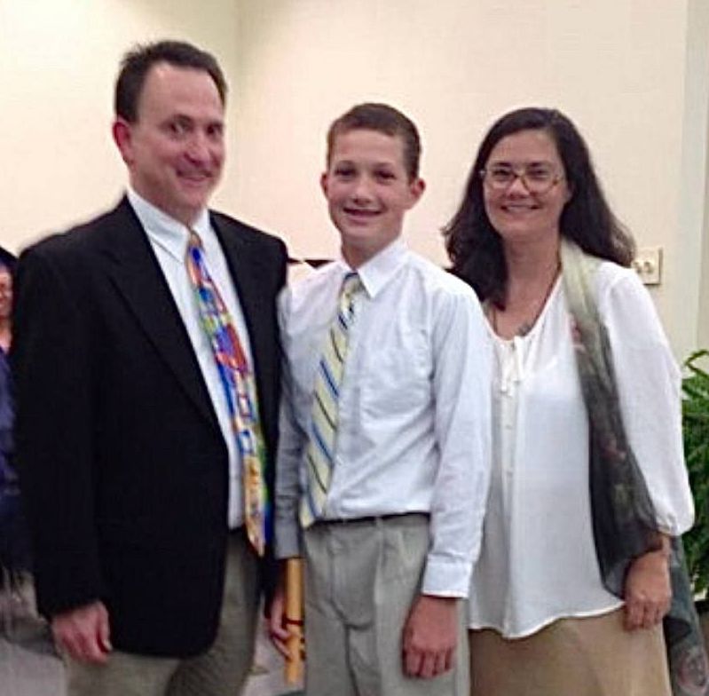 Three people posing indoors, wearing formal clothes and smiling at the camera.