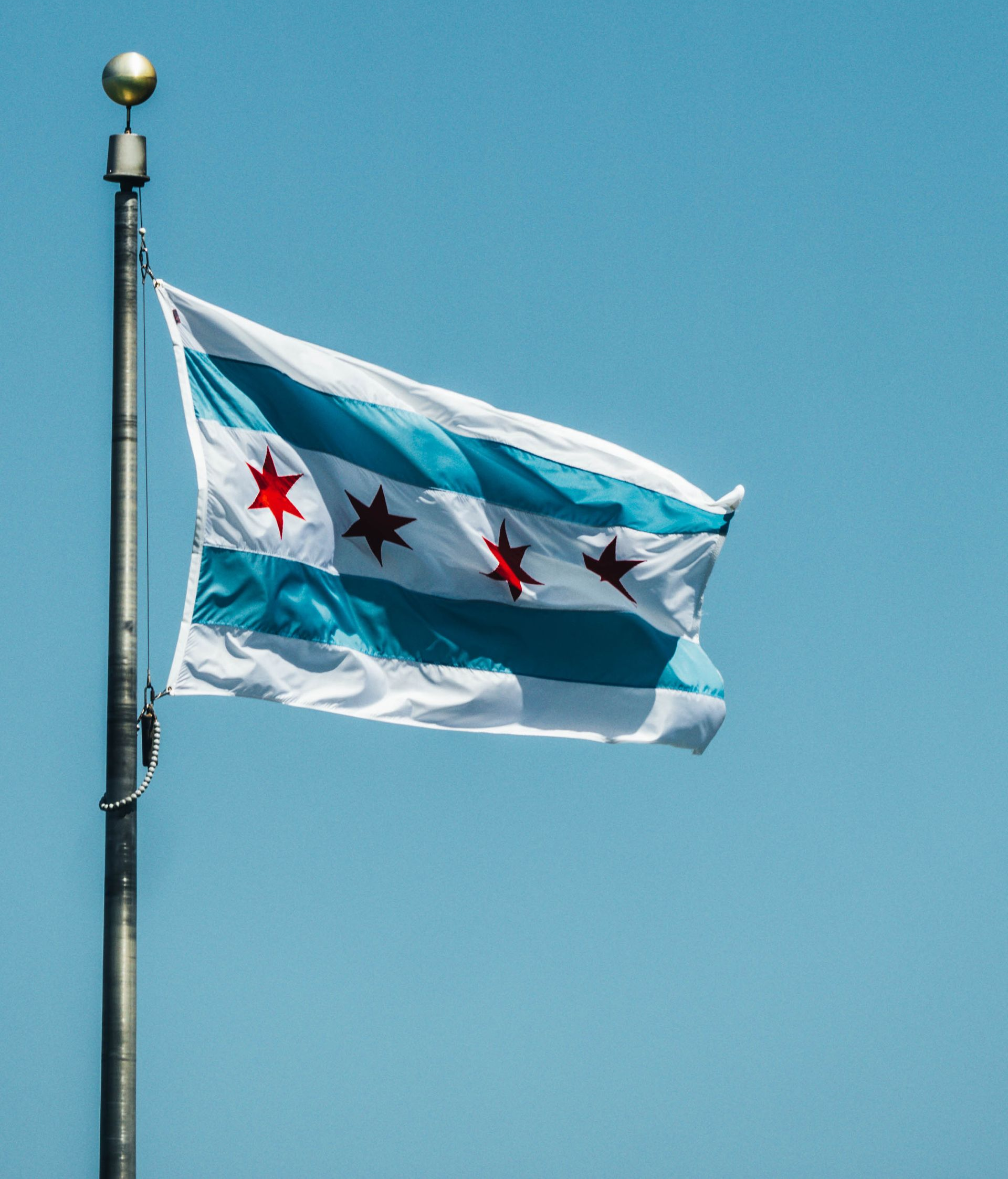 Chicago city flag waving on a pole against a blue sky