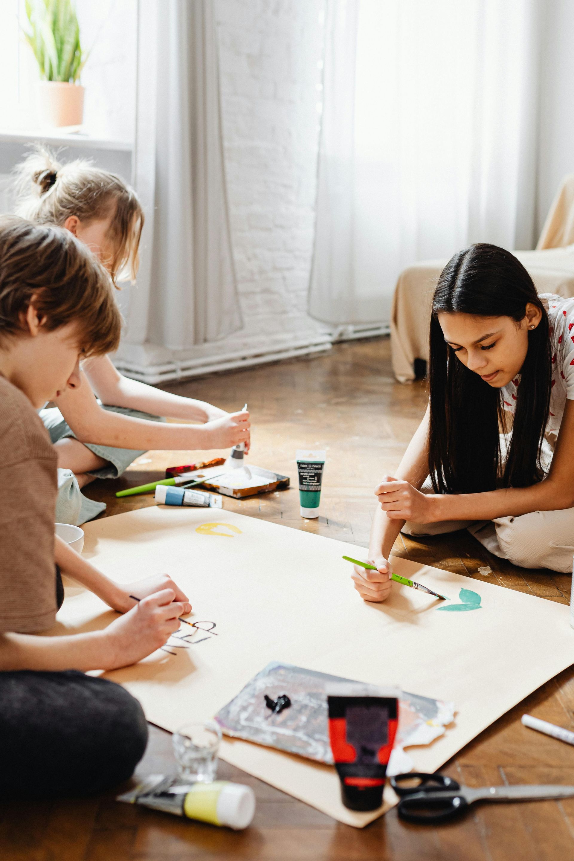 People seated on the floor crafting on large white paper in a bright room