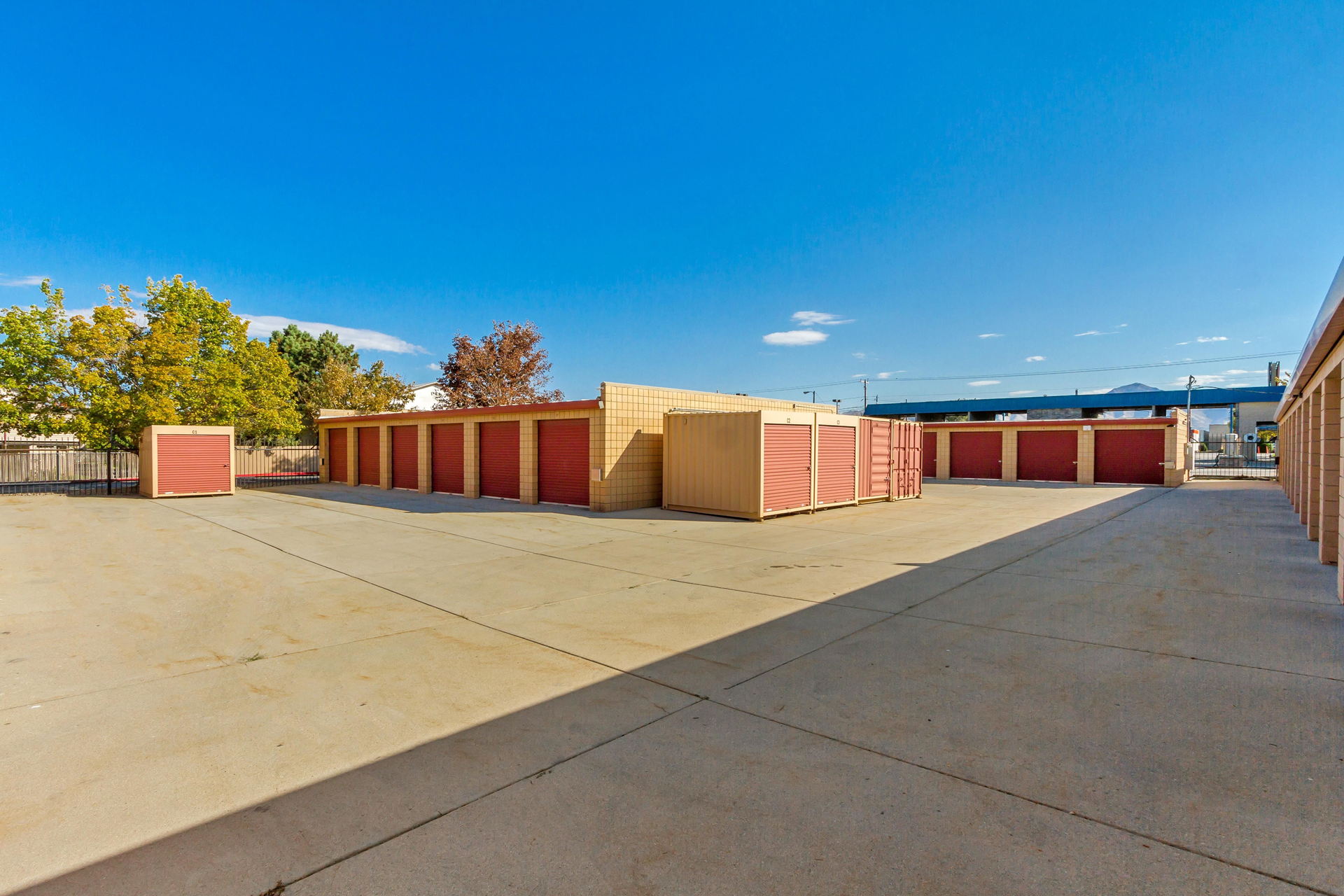 Storage units with red doors against a blue sky.