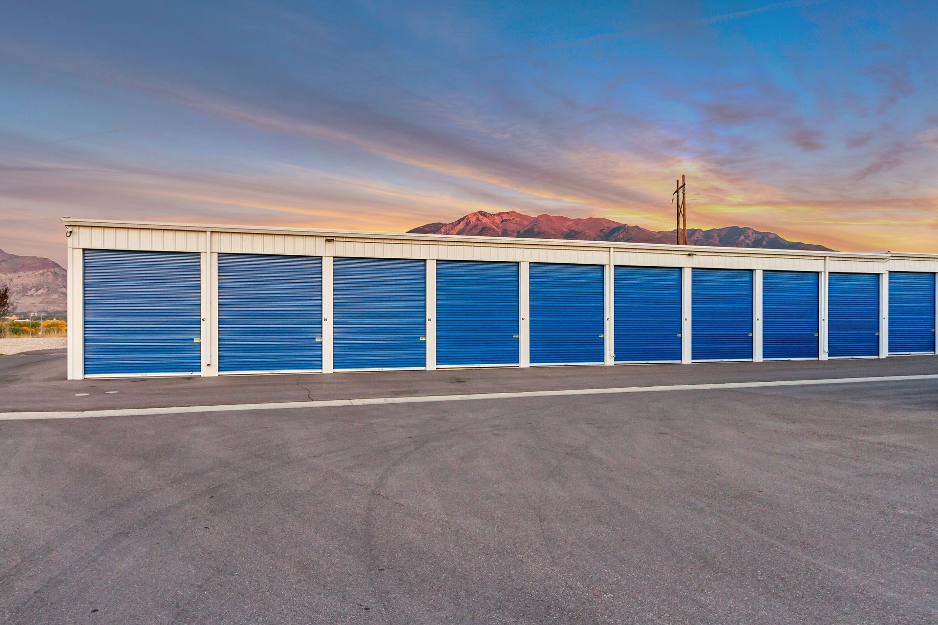 Blue storage units against a sunset sky, with a mountain in the background.