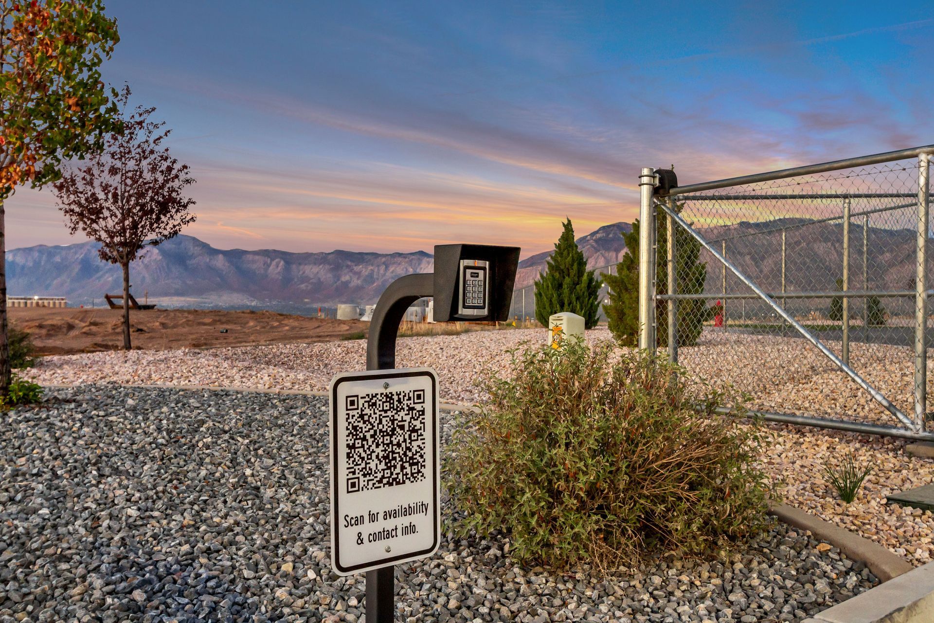 Dog waste station with QR code, set against a mountain view at sunset.