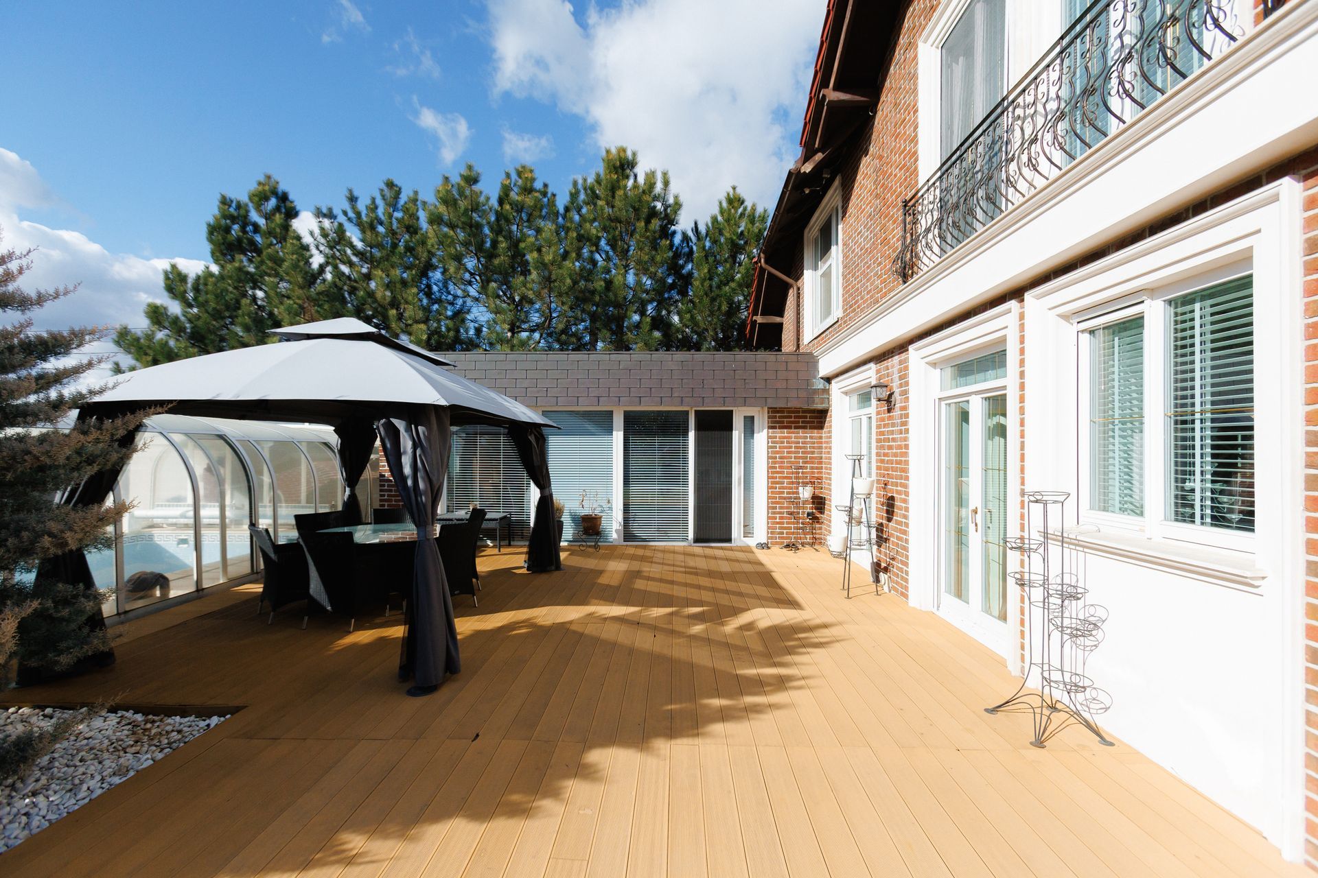 Outdoor wooden deck beside a house, with a patio umbrella and table under a clear blue sky.