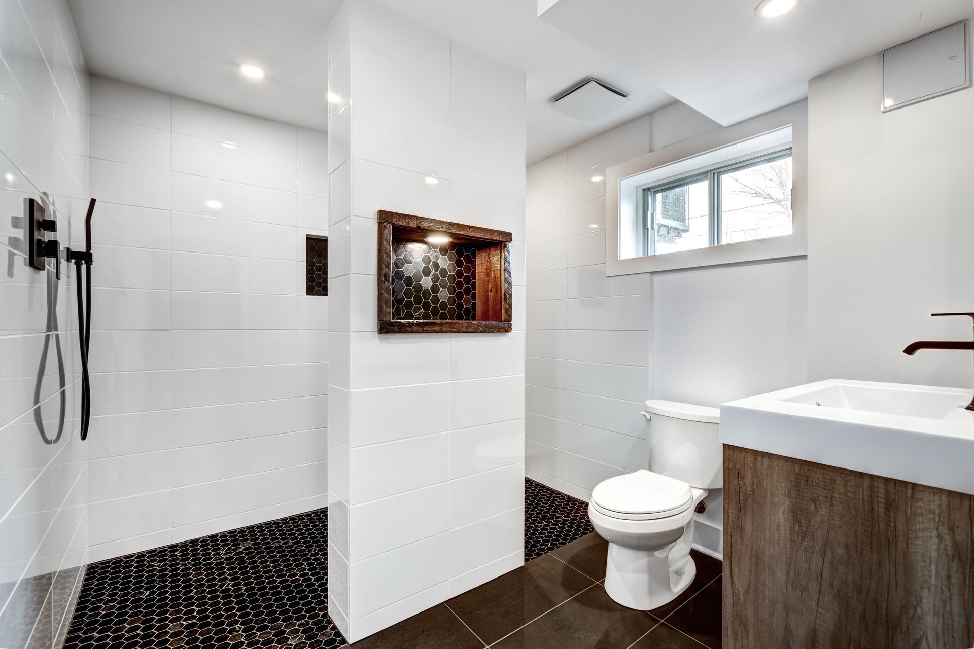 Modern white bathroom with walk-in shower, toilet, vanity, and window light