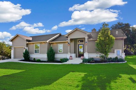 Suburban single-story house with beige siding, white trim, and a bright green lawn under a blue sky.