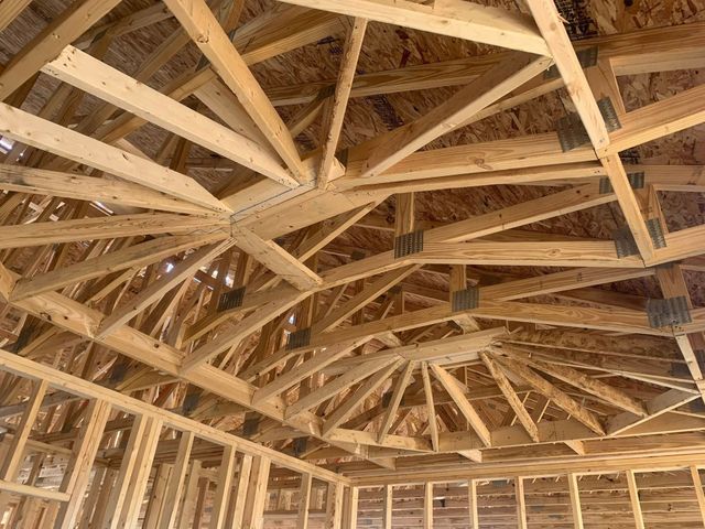 Exposed wooden roof trusses and framing in an unfinished attic or house interior