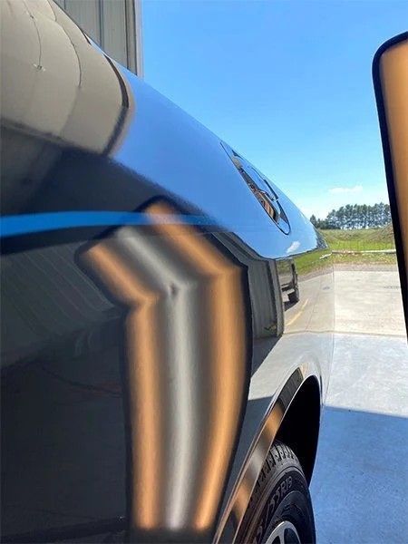 Close-up of a black SUV with blue trim parked on a sunny paved lot