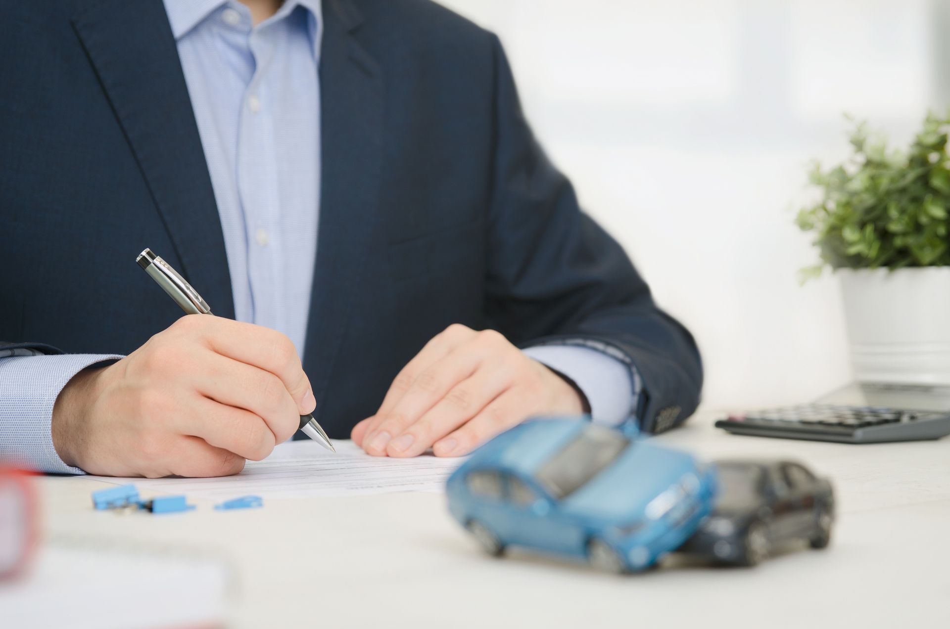 A man in a suit is sitting at a desk writing on a piece of paper.