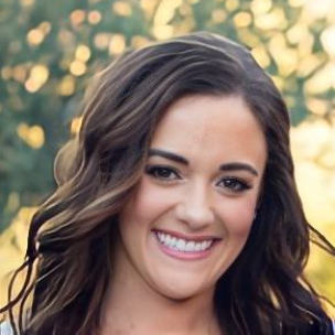 A woman with long brown hair is smiling for the camera.