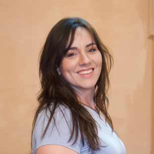 A woman with long brown hair is smiling for the camera.