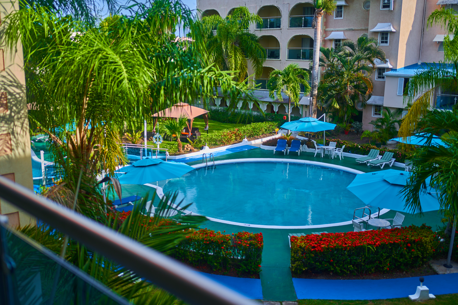 Resort pool with blue water, lounge chairs, palm trees, and a hotel building in the background