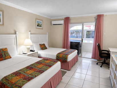 Bright bedroom with a white bed, turquoise accent wall, bedside lamps, and sliding doors to a balcony.