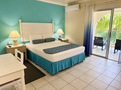Bright bedroom with a white bed, turquoise accent wall, bedside lamps, and sliding doors to a balcony.