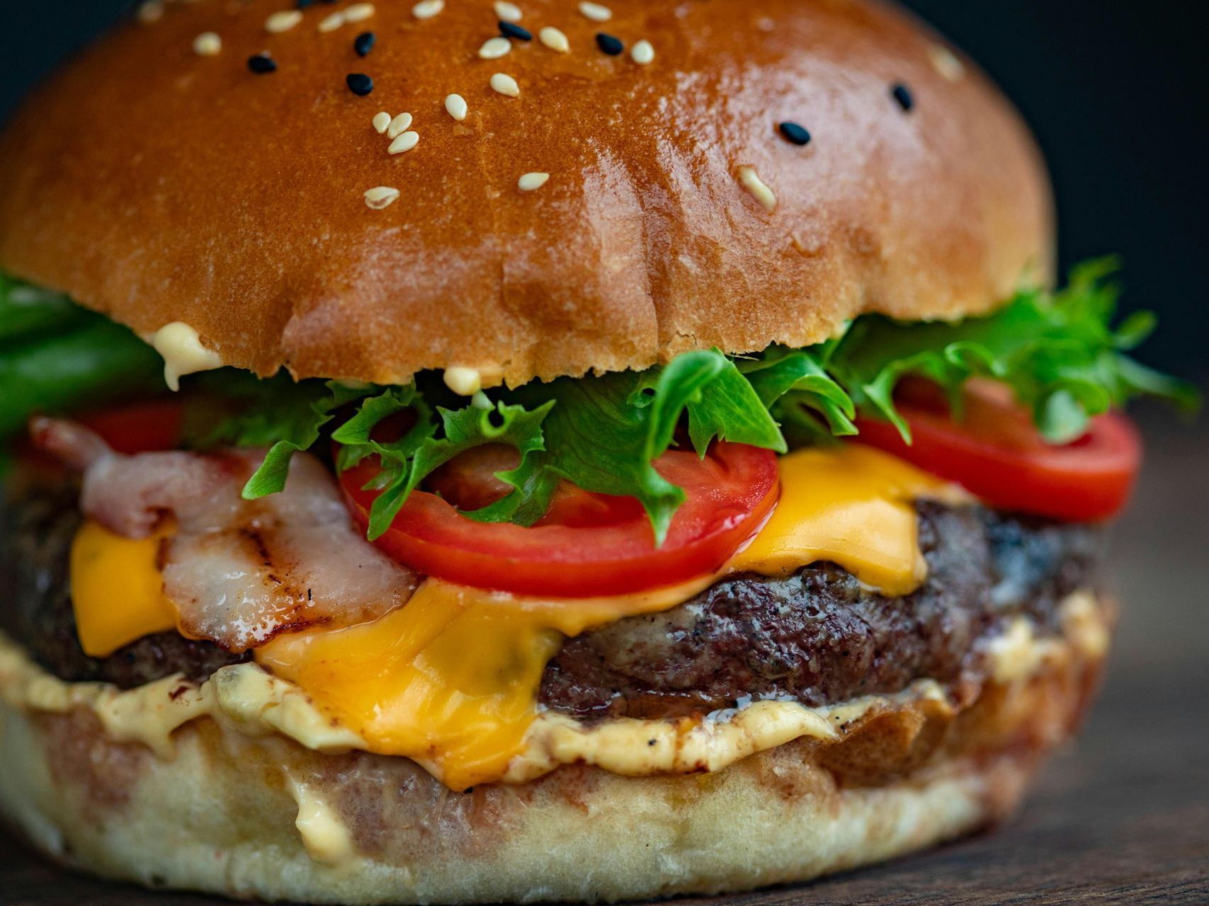 Sesame seed cheeseburger with lettuce, tomato, melted cheese, and beef patty on a bun