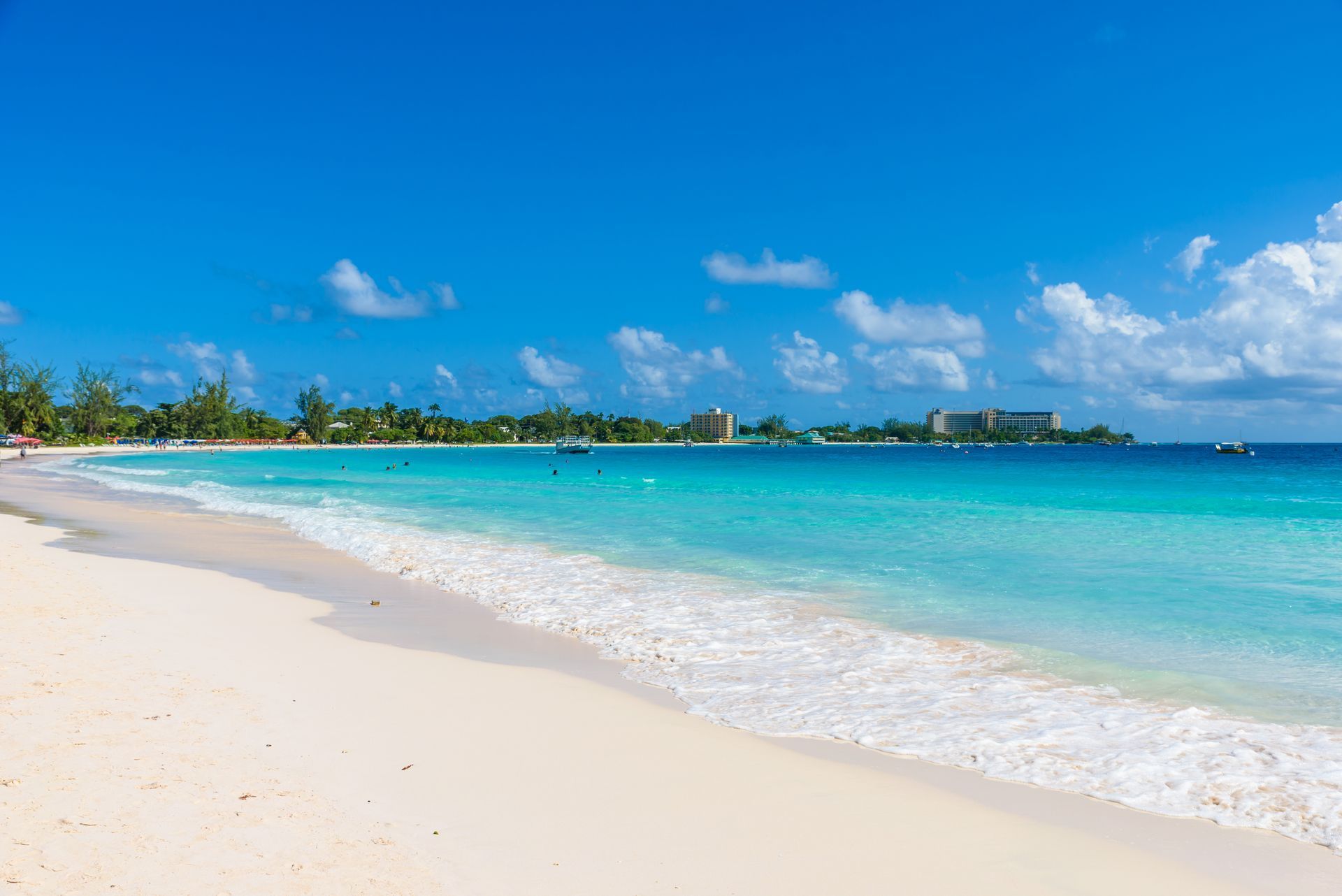 Sunny tropical beach with white sand, turquoise water, and palm trees under a blue sky