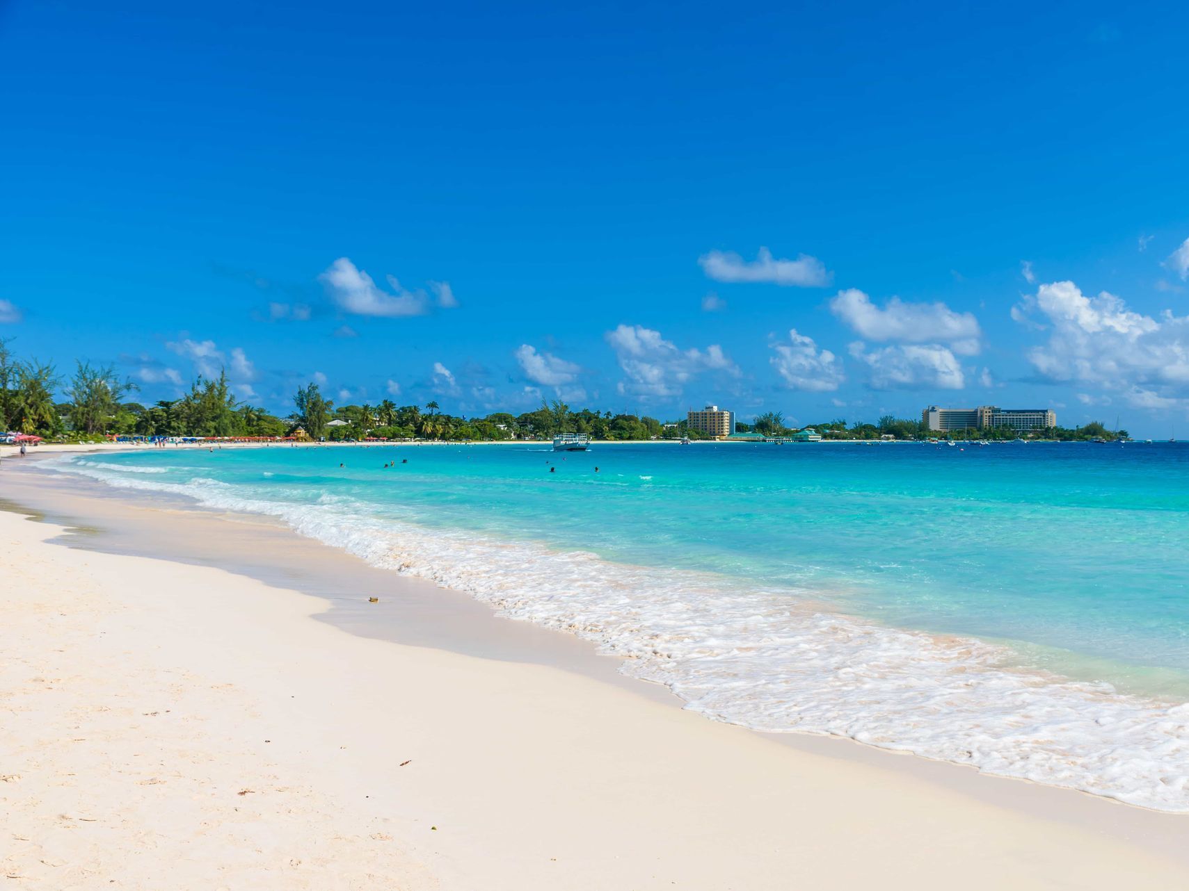 Sunny tropical beach with white sand, turquoise water, and a clear blue sky