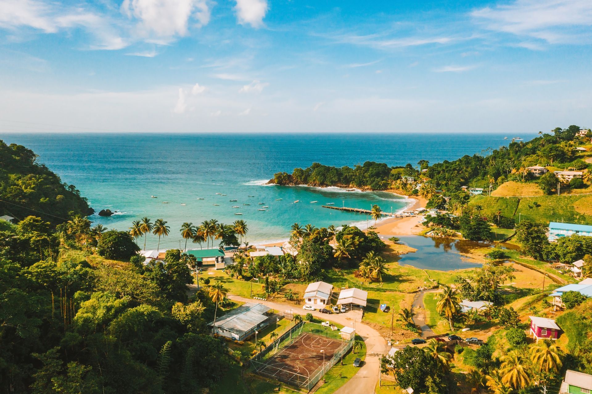 Tropical bay with turquoise water, sandy beach, and lush green hills under a bright sky