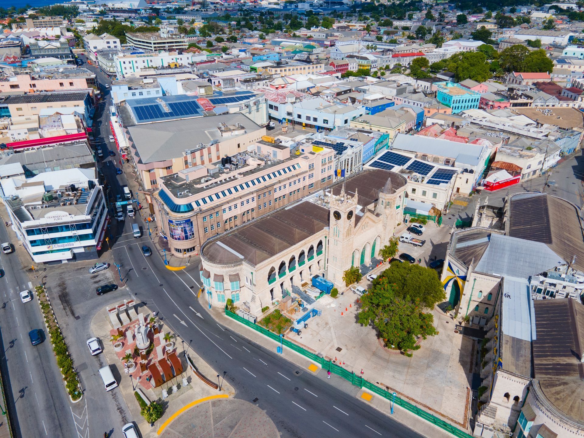Aerial view of a coastal town with roads, low-rise buildings, and a church-like building near the center.