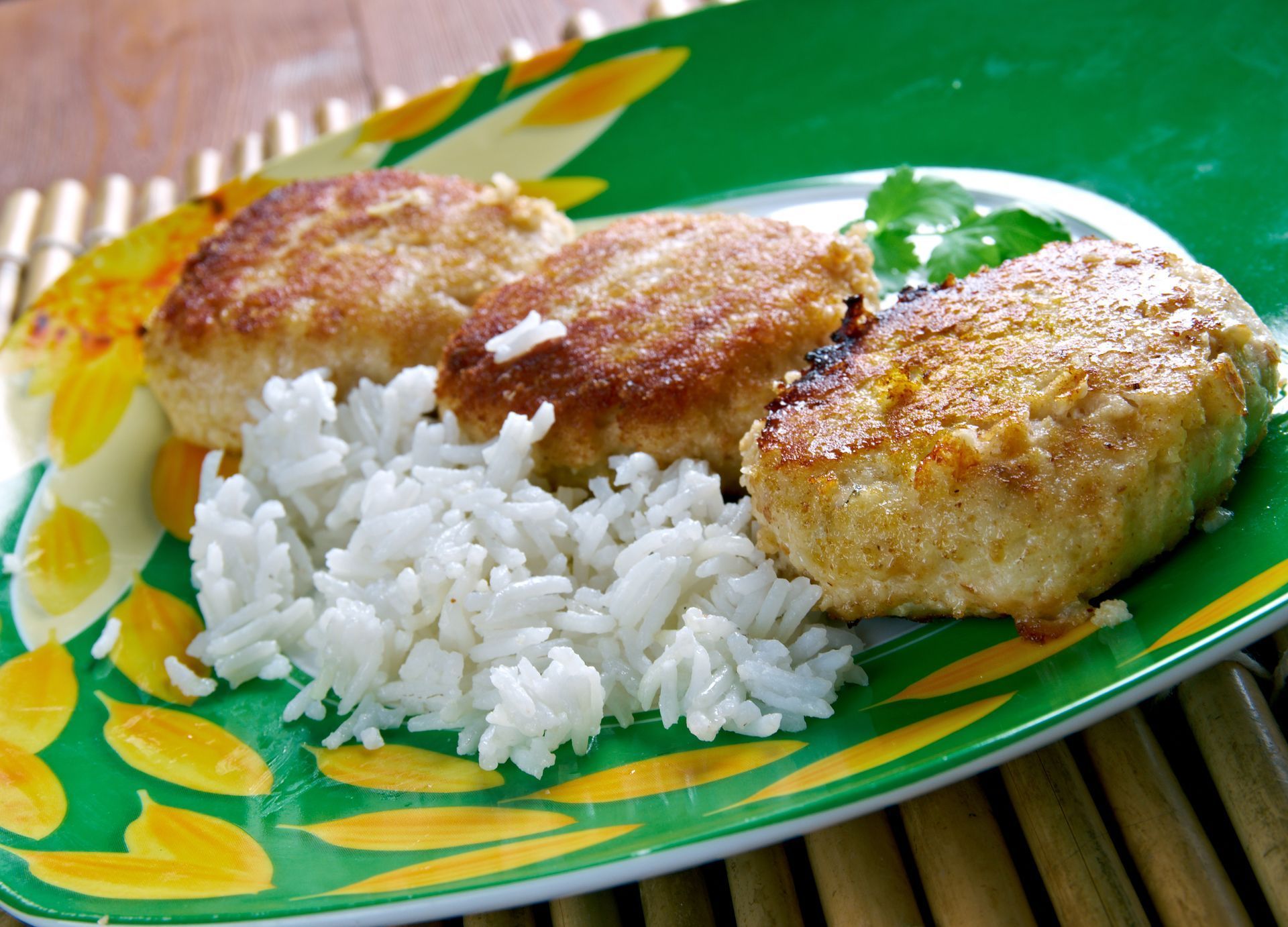 Grilled patties with white rice on a green floral plate