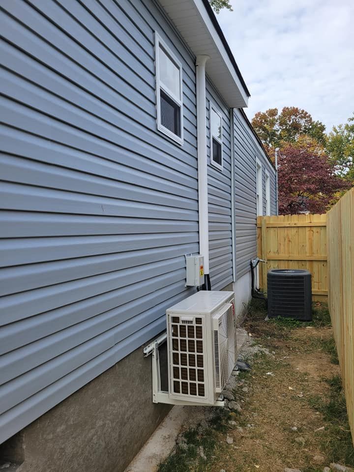 A blue house with a white air conditioner on the side of it.