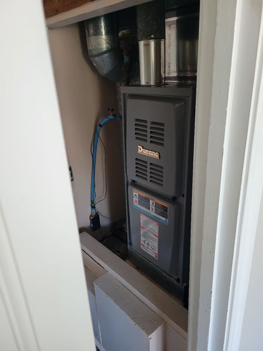 A furnace is sitting in a closet next to a door.